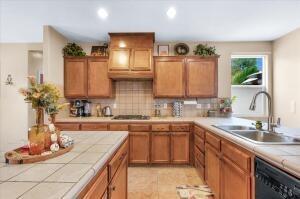 kitchen with tasteful backsplash, sink, light tile patterned floors, tile countertops, and dishwasher