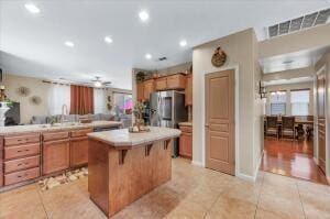 kitchen featuring stainless steel refrigerator, light tile patterned floors, tile countertops, a breakfast bar area, and a kitchen island