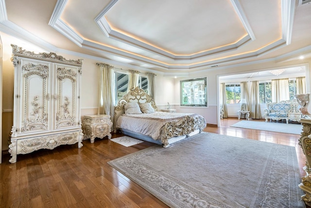 bedroom with crown molding, a tray ceiling, and hardwood / wood-style floors