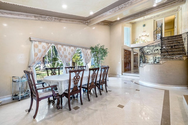 dining area featuring a healthy amount of sunlight, ornamental molding, a chandelier, and a high ceiling