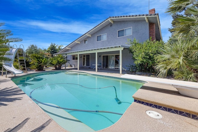 view of swimming pool featuring a water slide, a diving board, and a patio area