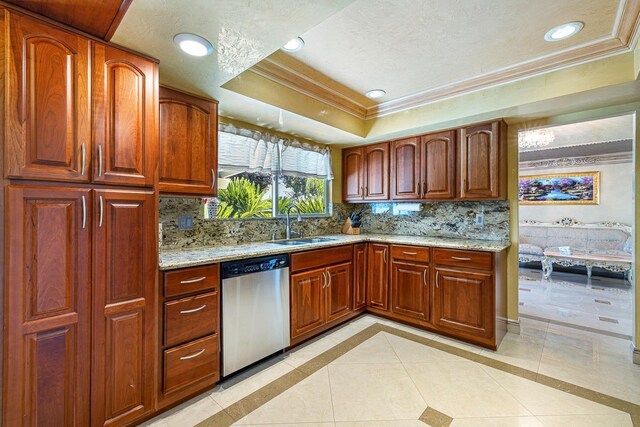 kitchen with light stone counters, stainless steel dishwasher, a raised ceiling, and tasteful backsplash