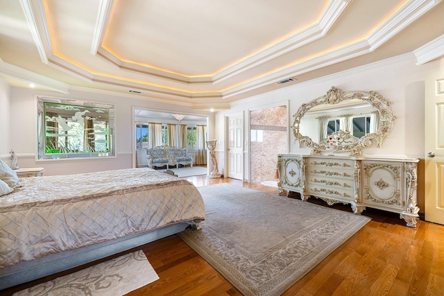 bedroom with crown molding, wood-type flooring, and a raised ceiling