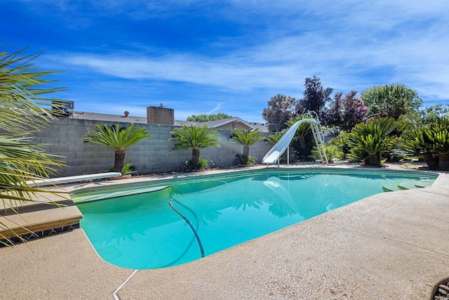 view of pool with a diving board and a water slide