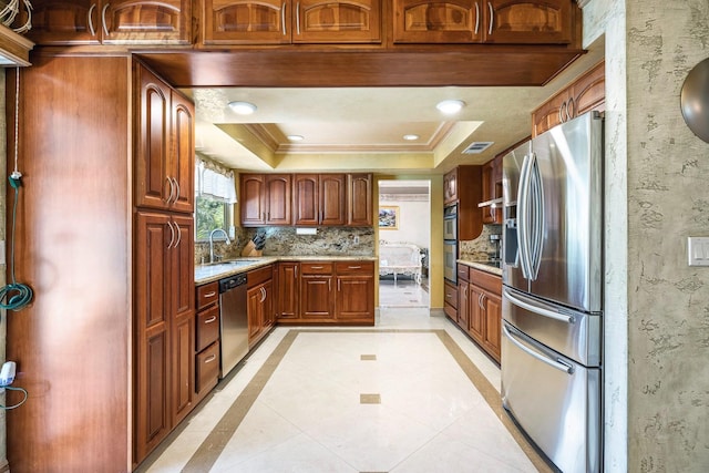 kitchen with appliances with stainless steel finishes, sink, backsplash, a raised ceiling, and light stone countertops