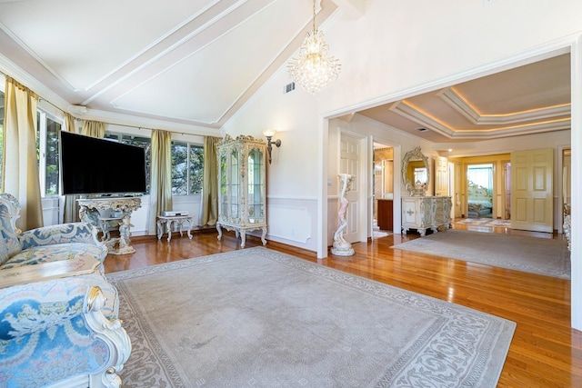 living room featuring hardwood / wood-style flooring, vaulted ceiling with beams, a tray ceiling, ornamental molding, and a chandelier