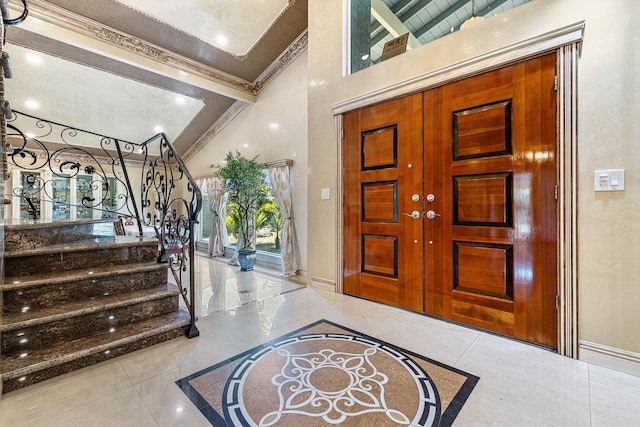 tiled foyer featuring a high ceiling and crown molding