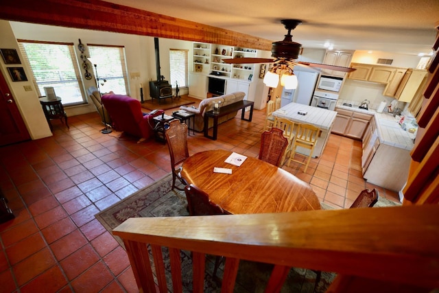 tiled dining room with ceiling fan and a wood stove