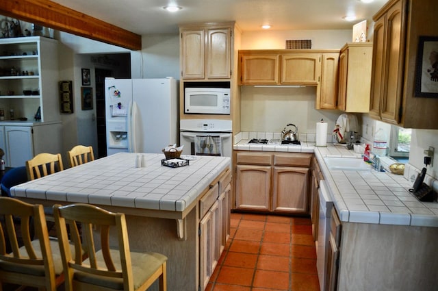 kitchen featuring a kitchen island, white appliances, tile countertops, and a breakfast bar area