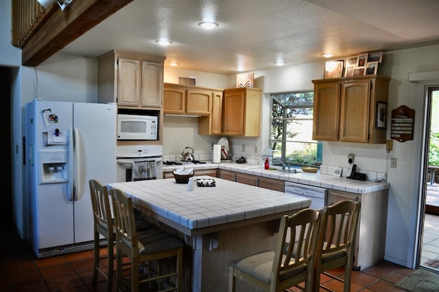 kitchen with white appliances, tile counters, a breakfast bar, and a kitchen island
