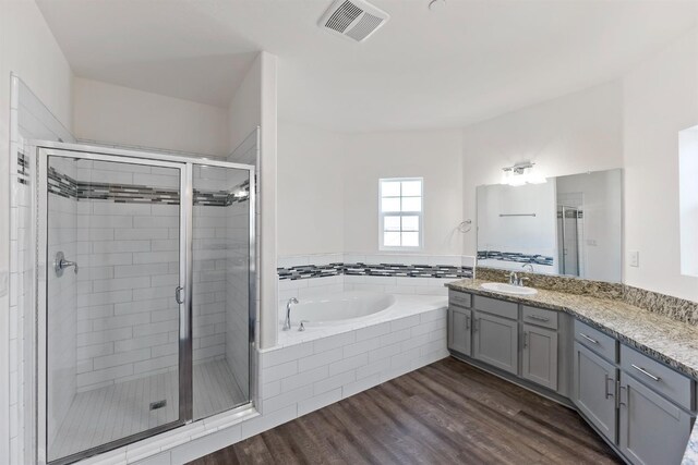 bathroom with plus walk in shower, hardwood / wood-style floors, and vanity