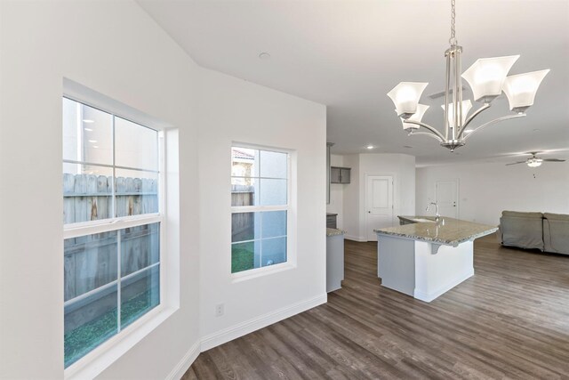 kitchen featuring sink, a kitchen breakfast bar, dark hardwood / wood-style floors, pendant lighting, and ceiling fan with notable chandelier