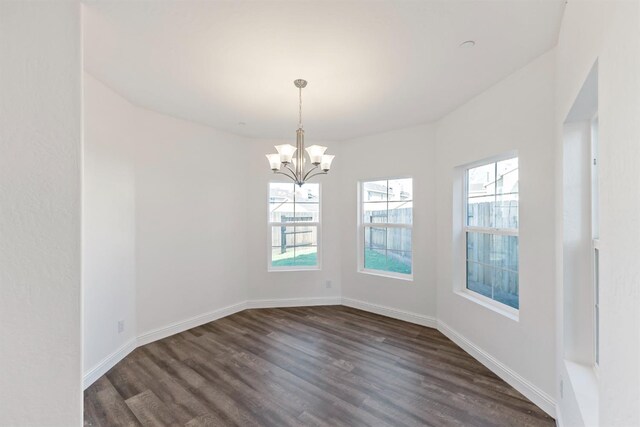 unfurnished dining area featuring dark wood-type flooring and an inviting chandelier