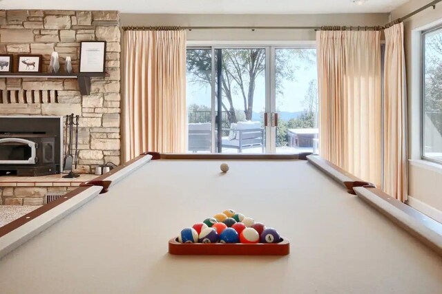 rec room with a wood stove, pool table, a fireplace, and a healthy amount of sunlight