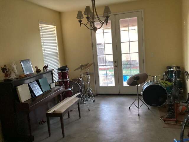 misc room with french doors, concrete flooring, and a notable chandelier