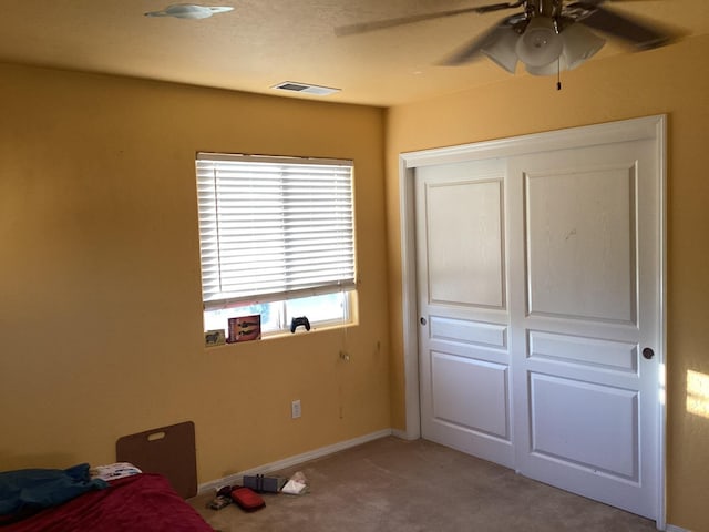 unfurnished bedroom featuring ceiling fan, a closet, and light colored carpet