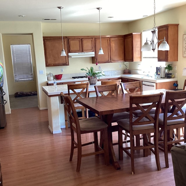 kitchen with dishwasher, pendant lighting, dark wood-type flooring, and a notable chandelier