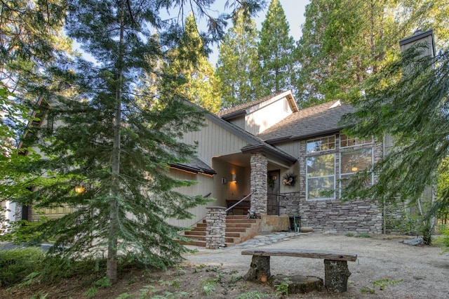 property entrance featuring stone siding and a shingled roof