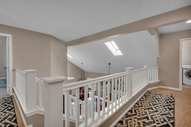 hall with washer / clothes dryer, vaulted ceiling with skylight, carpet, and a chandelier