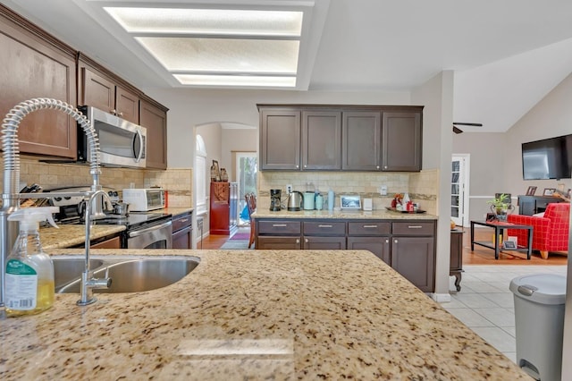 kitchen featuring backsplash, light wood-type flooring, and dark brown cabinets