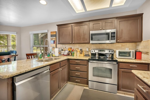 kitchen featuring appliances with stainless steel finishes, sink, tasteful backsplash, and light stone counters