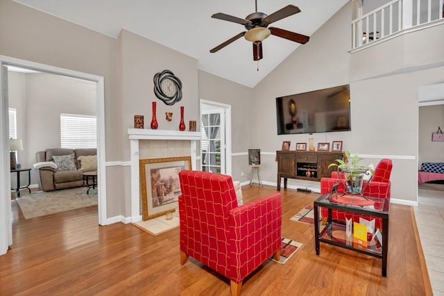 living room featuring ceiling fan, wood-type flooring, high vaulted ceiling, and a fireplace