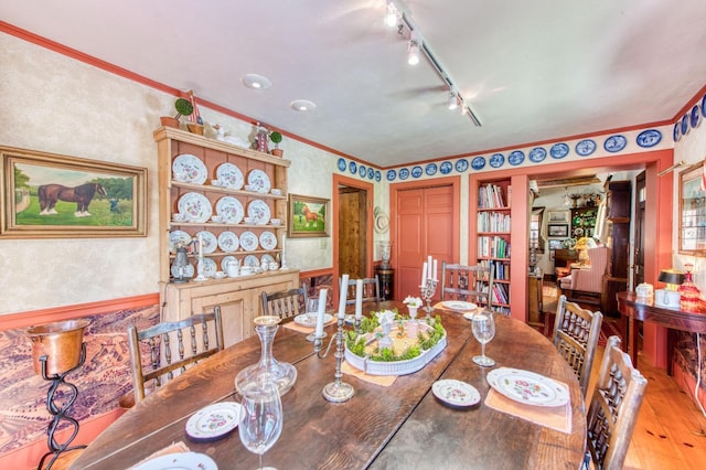 dining room with rail lighting, light wood finished floors, and ornamental molding