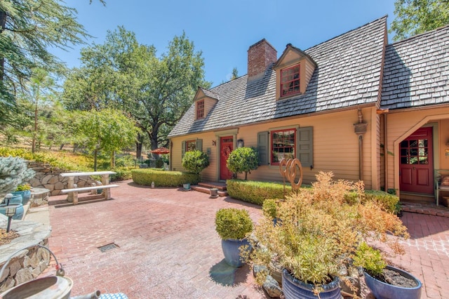 cape cod house with a patio and a chimney