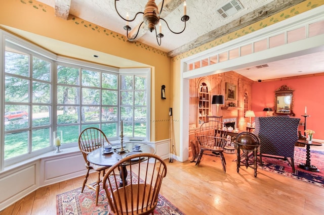 dining area with light wood-type flooring, visible vents, and an inviting chandelier