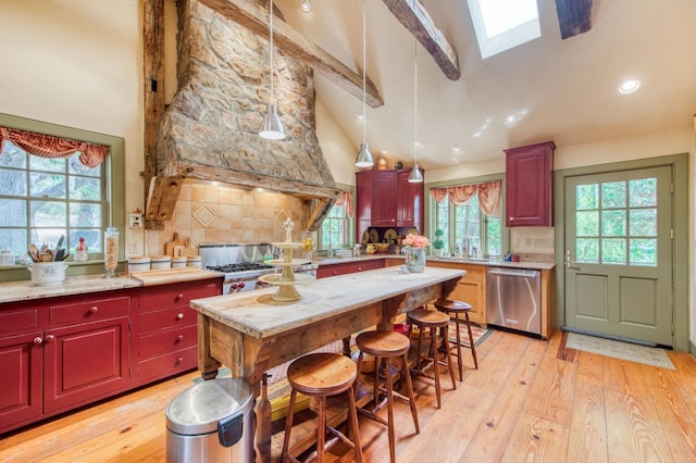 kitchen featuring light wood finished floors, a skylight, a sink, dishwasher, and tasteful backsplash