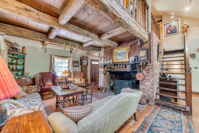 living room featuring stairway, an inviting chandelier, beam ceiling, a fireplace, and wooden ceiling