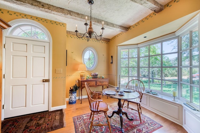 dining area featuring beamed ceiling, baseboards, an inviting chandelier, and light wood finished floors