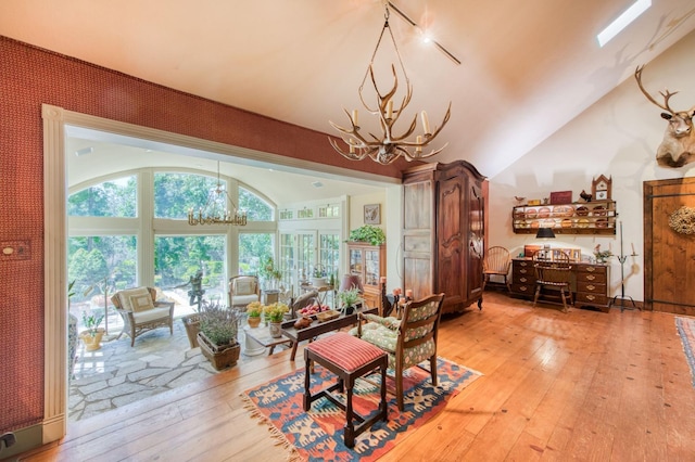 living room featuring lofted ceiling, a notable chandelier, and light wood finished floors