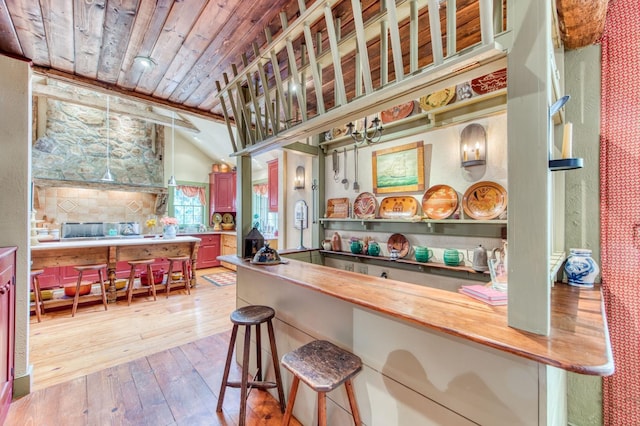 kitchen featuring butcher block counters, a breakfast bar, lofted ceiling, hardwood / wood-style floors, and wooden ceiling