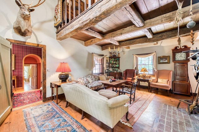 living room with baseboards, beamed ceiling, wood ceiling, hardwood / wood-style floors, and arched walkways