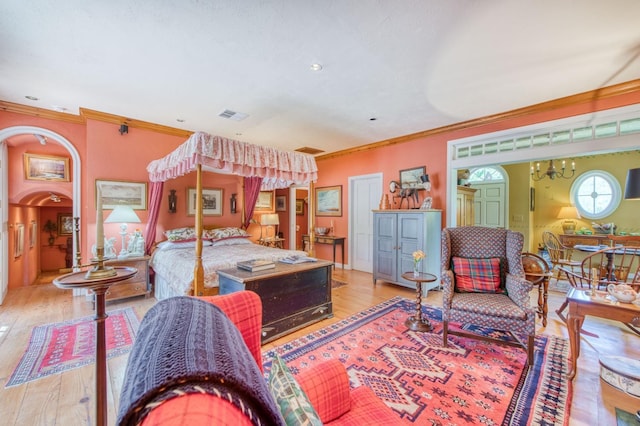 bedroom with a notable chandelier, visible vents, wood finished floors, and ornamental molding