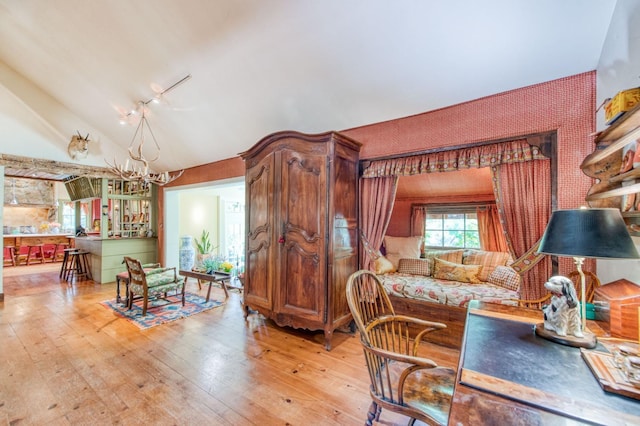 dining area featuring light wood finished floors, a chandelier, wallpapered walls, and vaulted ceiling