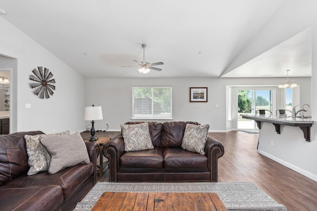 living room featuring wood-type flooring, vaulted ceiling, and ceiling fan with notable chandelier