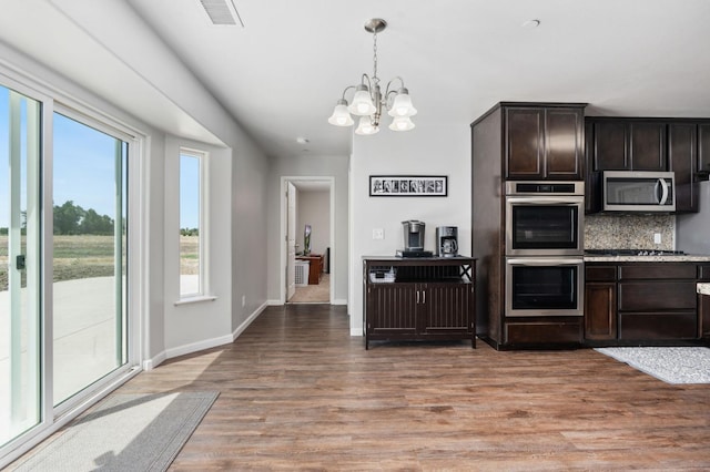 kitchen with backsplash, a notable chandelier, dark brown cabinetry, appliances with stainless steel finishes, and light hardwood / wood-style floors