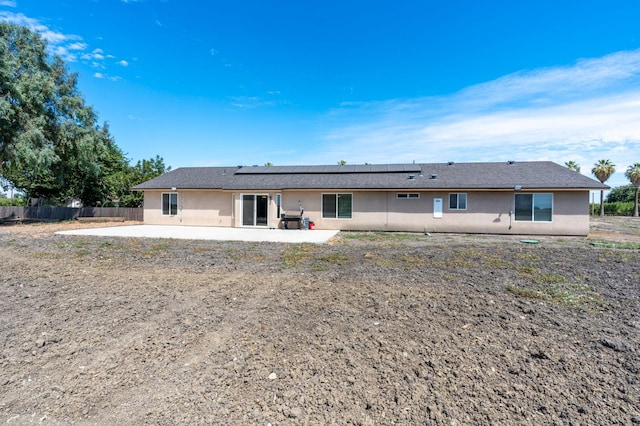 rear view of property with a patio area and solar panels