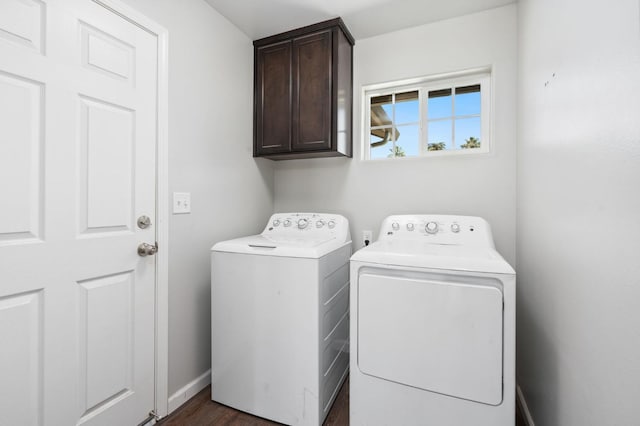 clothes washing area with washing machine and dryer, cabinets, and dark hardwood / wood-style flooring