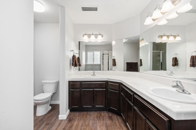 bathroom featuring toilet, hardwood / wood-style floors, a shower with shower door, and vanity