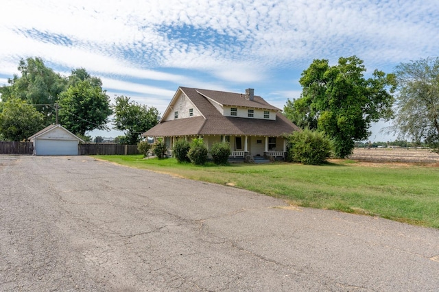 farmhouse featuring a porch, an outdoor structure, a front lawn, and a garage