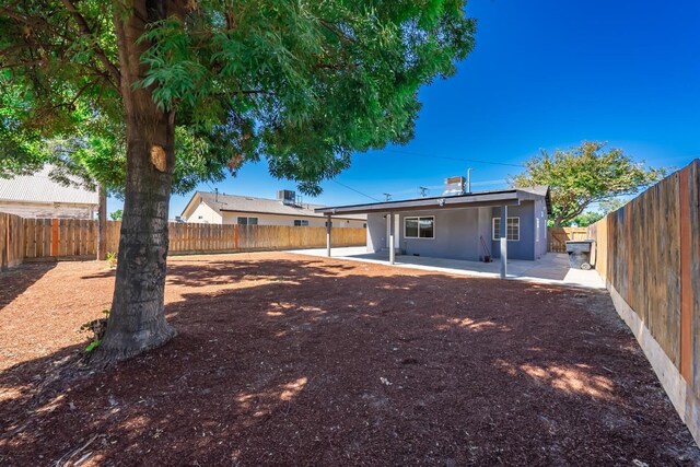 1845 N 10th Ave, Hanford, CA 93230 - back of house featuring a patio area, a fenced backyard, stucco siding, and solar panels