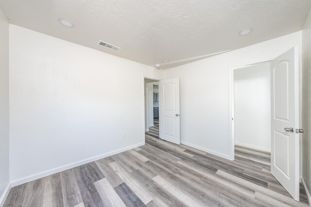 1845 N 10th Ave, Hanford, CA 93230 - unfurnished bedroom with light wood finished floors, baseboards, a textured ceiling, and recessed lighting