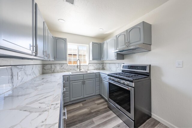 1845 N 10th Ave, Hanford, CA 93230 - kitchen featuring stainless steel gas range oven, gray cabinetry, under cabinet range hood, a sink, and tasteful backsplash
