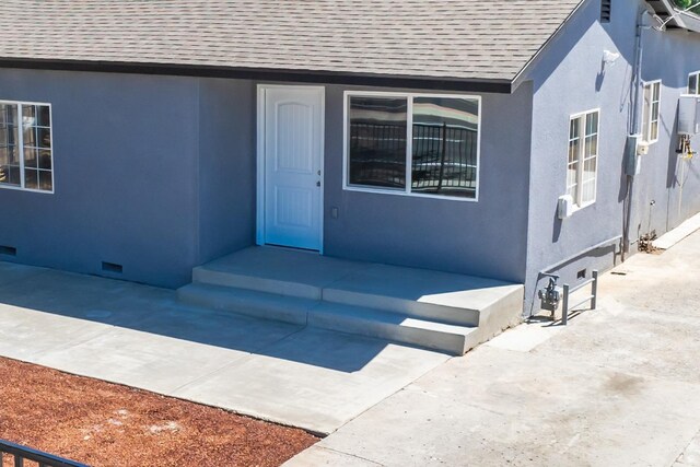 1845 N 10th Ave, Hanford, CA 93230 - view of exterior entry with a shingled roof, stucco siding, and crawl space