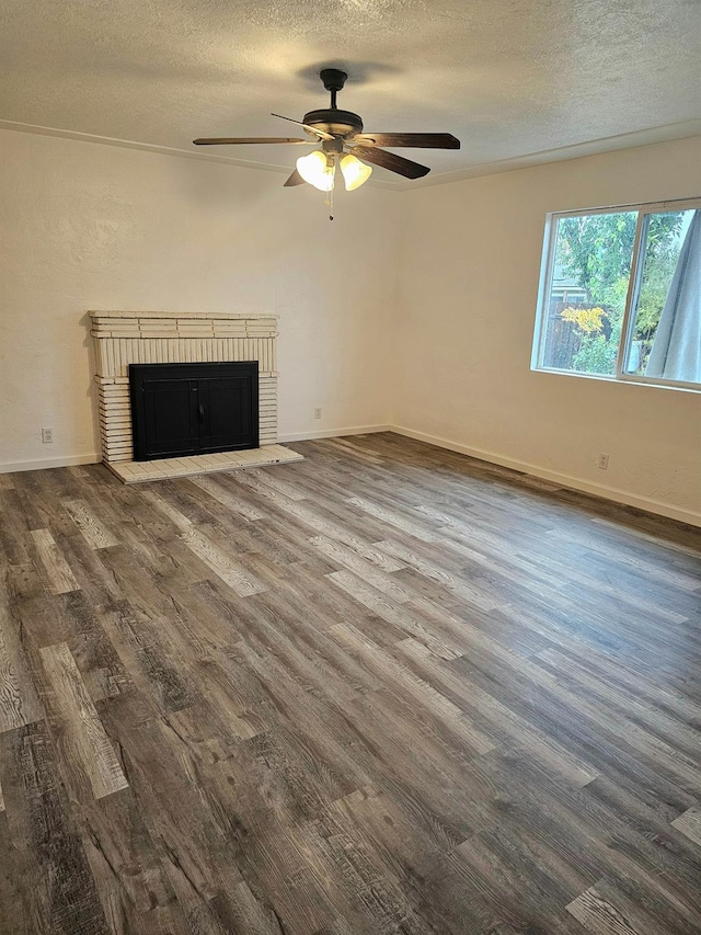 unfurnished living room featuring a textured ceiling, ceiling fan, a fireplace, and dark wood-type flooring