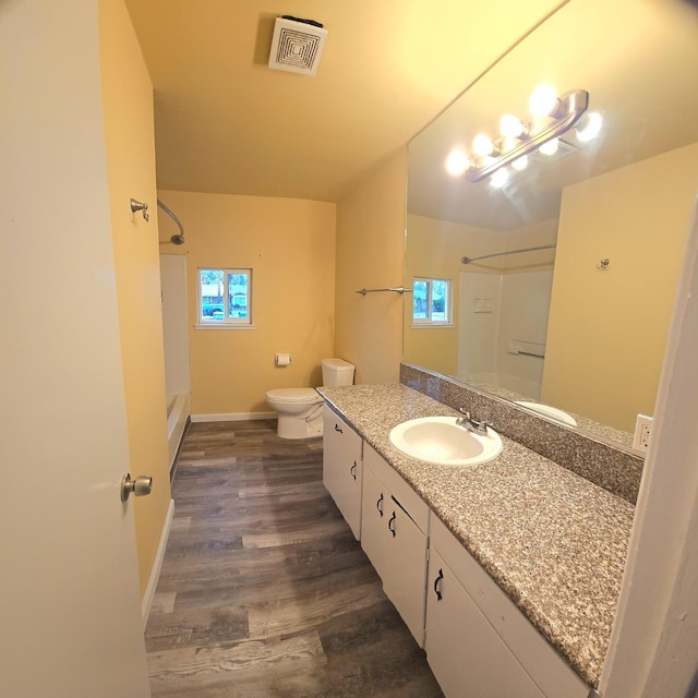 bathroom featuring toilet, vanity, a healthy amount of sunlight, and hardwood / wood-style flooring