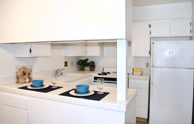 kitchen with white appliances, white cabinetry, and tile countertops